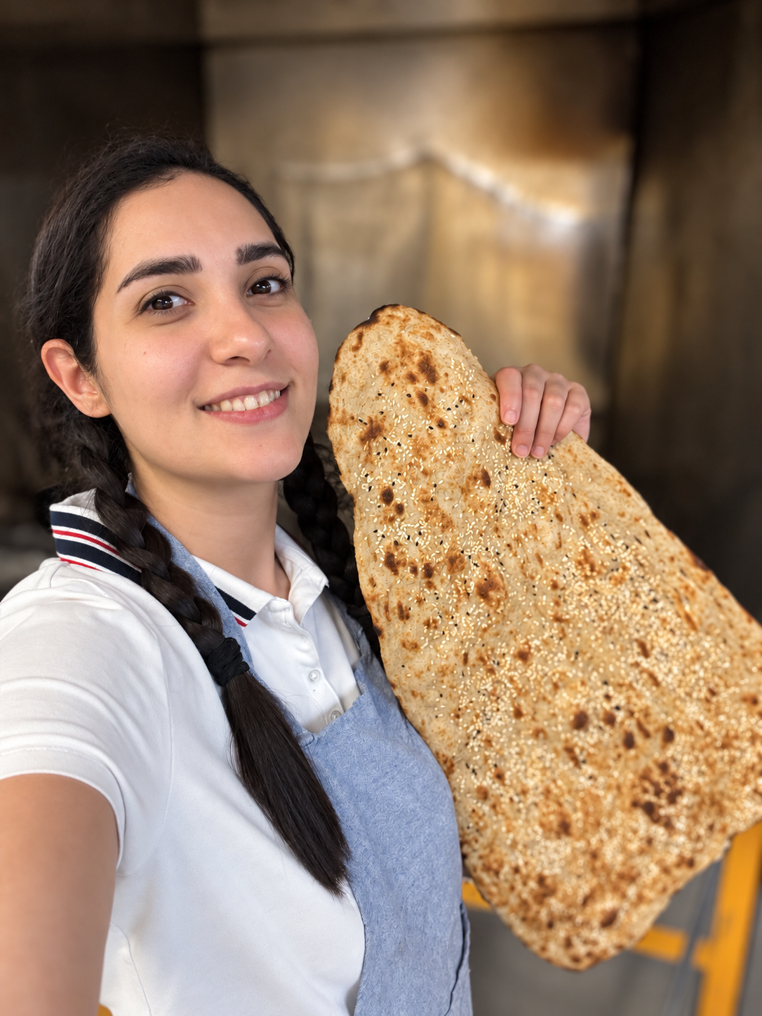 Sara holding freshly baked Persian flatbread in a warm bakery